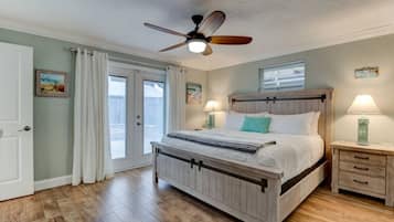 A bedroom with a wooden bed, a ceiling fan, a nightstand with a lamp, and a window with blinds.