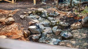 A natural outdoor setting with a small water feature surrounded by rocks and pebbles. - H2O Oasis Tree House (Pittsboro)