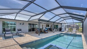 A covered outdoor swimming pool with lounge chairs and a patio area.