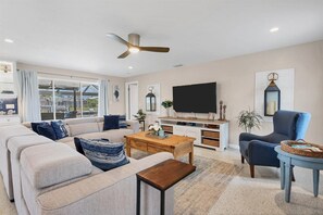 Un salon avec un canapé, une table basse, un téléviseur et un fauteuil.