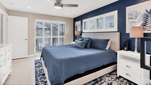 A bedroom with a bed, a nightstand, a dresser, a ceiling fan, and a window with blinds.