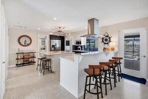 Une cuisine moderne dotée d’un îlot central, de tabourets de bar et offrant une vue sur l’extérieur.