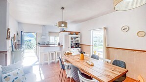 Een moderne keuken met witte kasten, een houten eettafel en een groot raam.