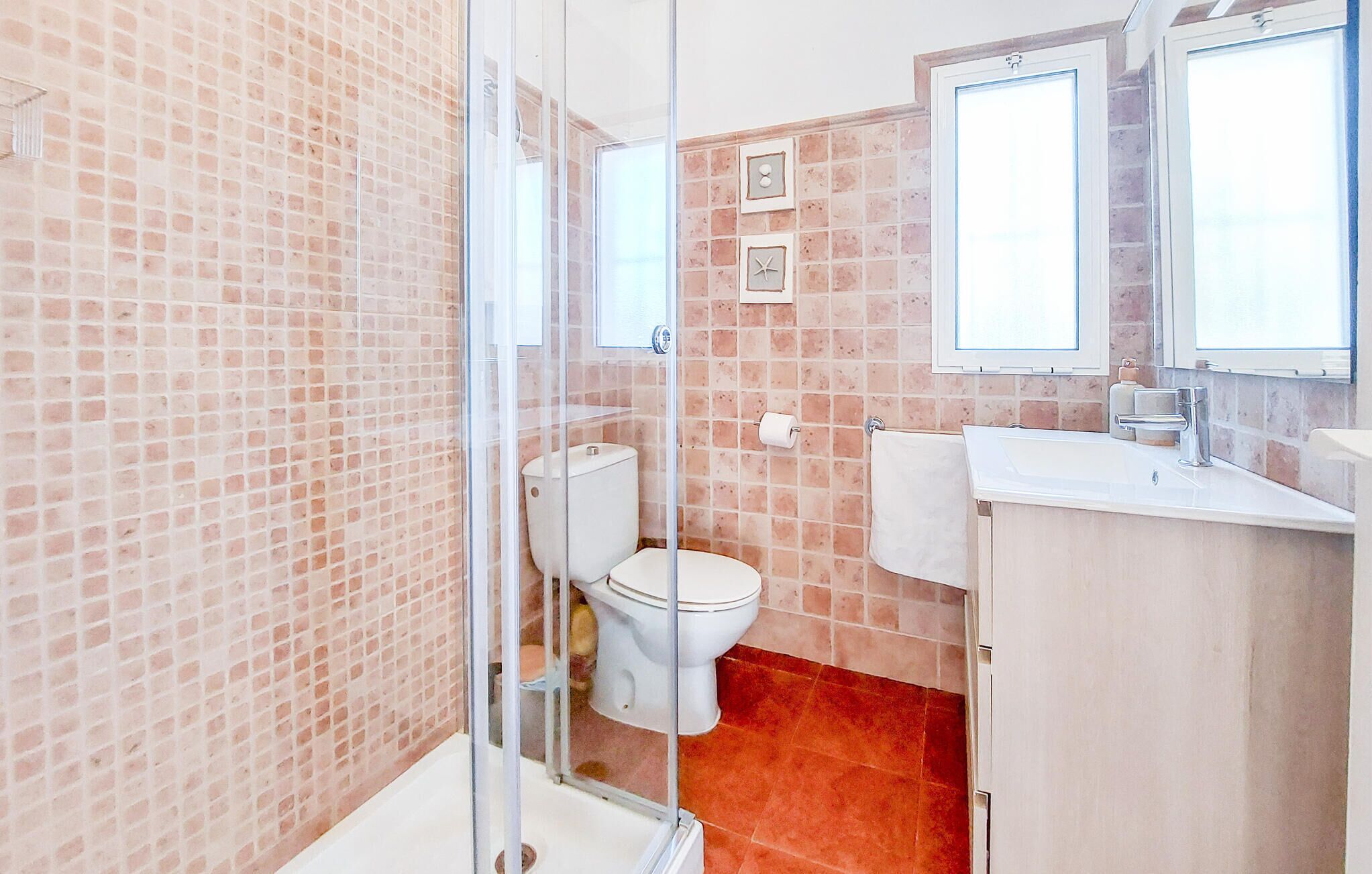 Un baño con inodoro, lavabo y zona de ducha.