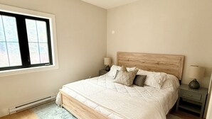 Ein Schlafzimmer mit einem hölzernen Bett, einem Nachttisch, einer Lampe und einem Fenster.