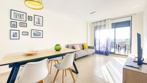 Uma sala de estar moderna com área de jantar, sofá, televisão e varanda com vista.