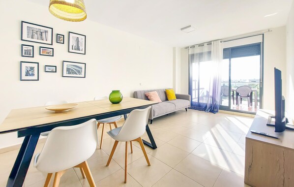 Una sala de estar moderna con comedor, un sofá, un televisor y un balcón con vistas.
