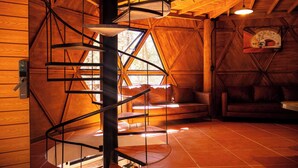 Una escalera de caracol en una cabaña de madera con una ventana y una chimenea.