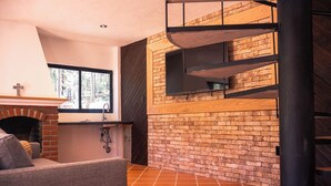 Un interior moderno con pared de ladrillo, chimenea, sofá y escalera.