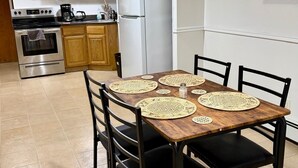 A dining area with a wooden table, four chairs, and woven placemats. - Serene 2-bedroom apartment in Astoria perfect for your getaway (Astoria)