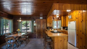 L’intérieur d’une cabane en bois comprend un coin repas, une cuisine et de grandes fenêtres.