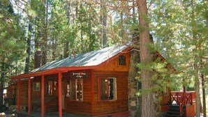 Une cabane en rondins avec un porche, un escalier et une petite terrasse.