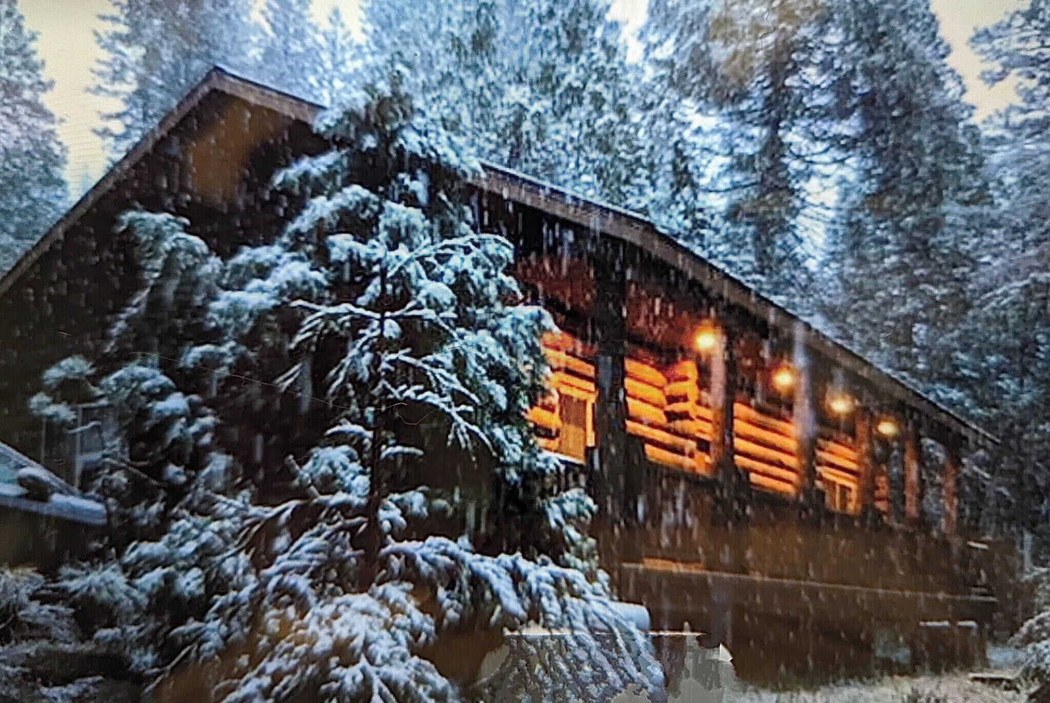A log cabin with a snow-covered exterior and a warm interior light.
