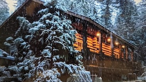 A log cabin with a snow-covered exterior and a warm interior light. - The Mini Cabin (Yosemite National Park)