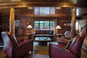 A cozy cabin interior with wooden walls, a sofa, leather chairs, and a coffee table. - Wapiti (Yosemite National Park)