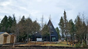 Une maison moderne à l’extérieur sombre, entourée d’une forêt.