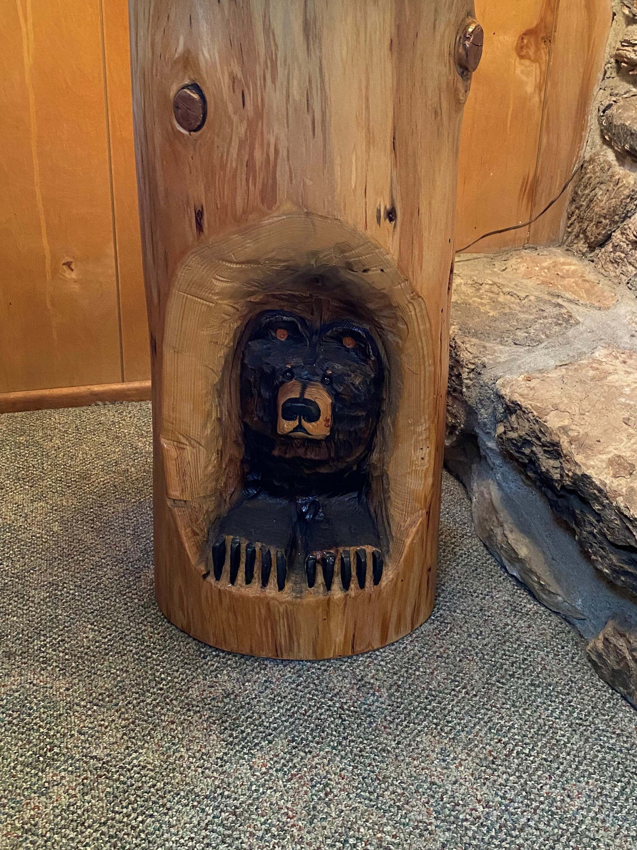 A wooden sculpture of a bear's face carved into a tree trunk.