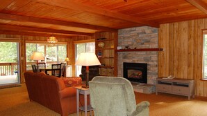 A cozy living room with a fireplace, wooden walls, and a dining area with a table and chairs. - Mountain Retreat (Yosemite National Park)