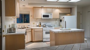 A modern kitchen with a central island, built-in microwave, and a gas stove. - The Last Resort (Yosemite National Park)