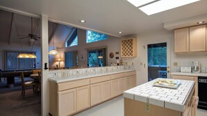 A modern kitchen with a central island, pendant lighting, and a view of the outdoors. - The Last Resort (Yosemite National Park)