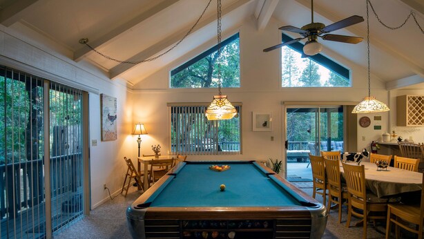 A pool table in a room with high ceilings, large windows, and a dining area. - The Last Resort (Yosemite National Park)