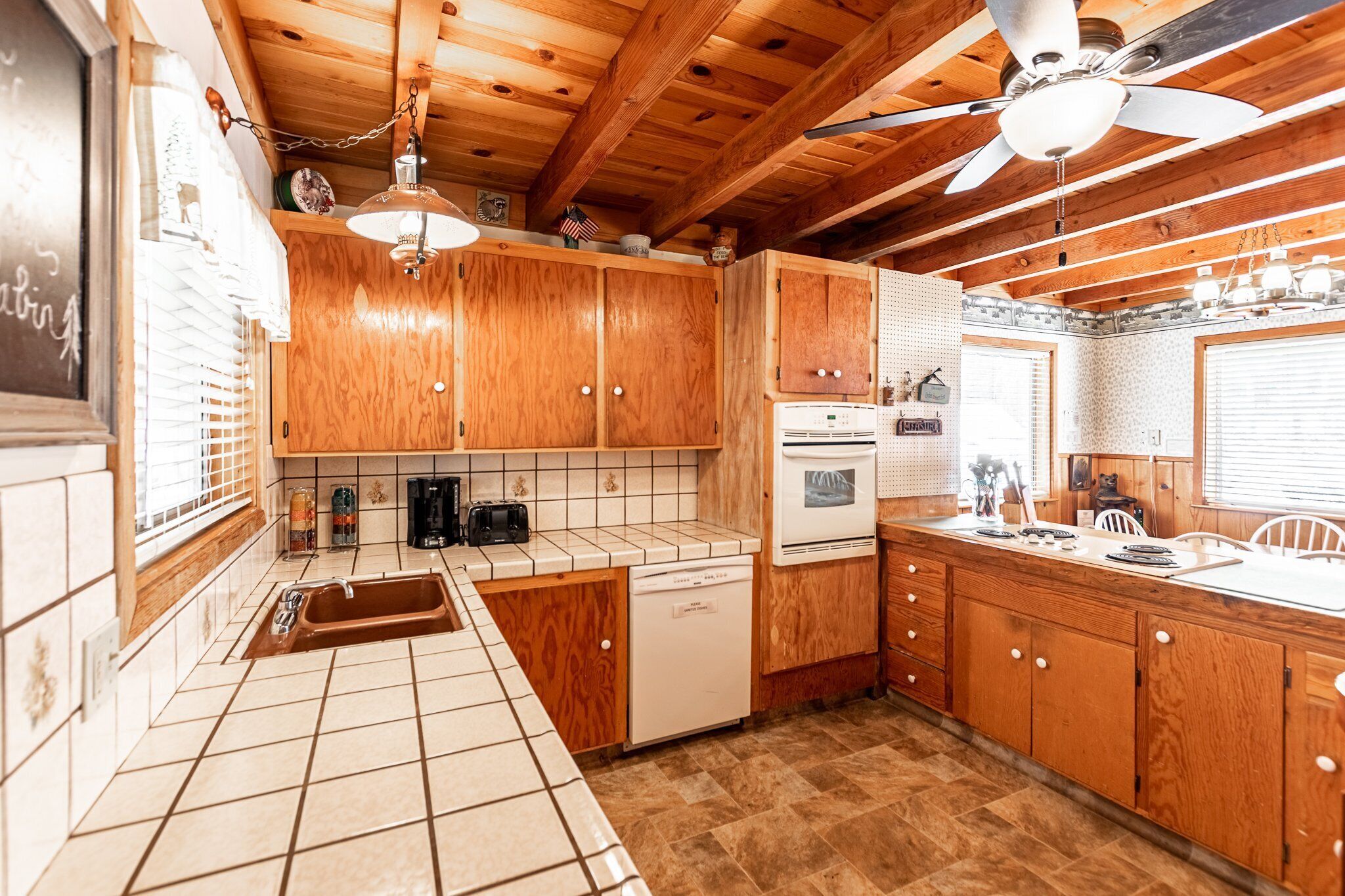 A kitchen with wooden cabinets, a dishwasher, a stove, and a ceiling fan.