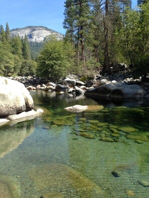 A clear river with rocks and trees, surrounded by a mountainous landscape. - Grant's Camp (Yosemite National Park)