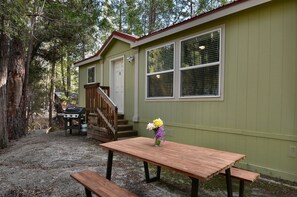 A small, single-story building with a green exterior and a wooden deck. - Suter's Forte (Yosemite National Park)