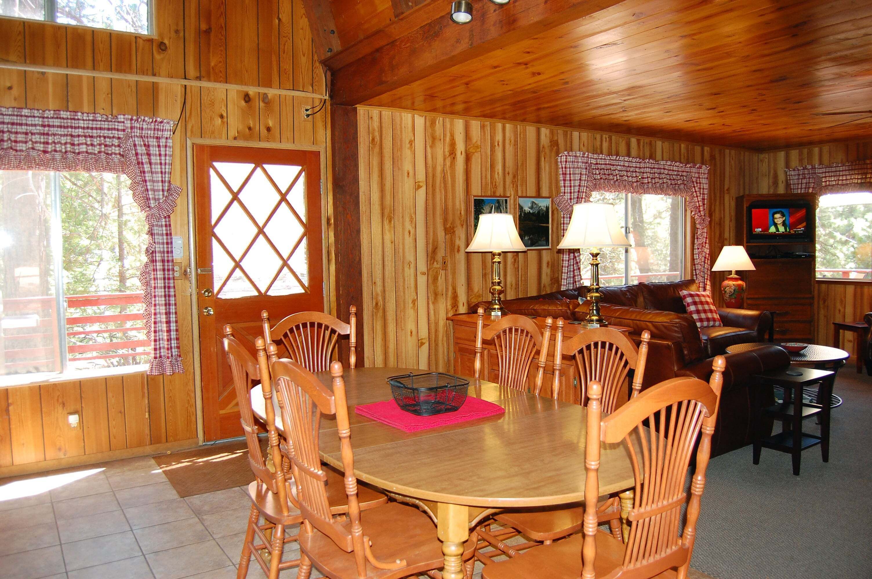 Ein Holzinterieur mit Esstisch, Stühlen, einer Couch und einem Fernseher.
