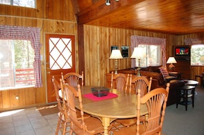 Un intérieur en bois comprenant une table à manger, des chaises, un canapé et un téléviseur.