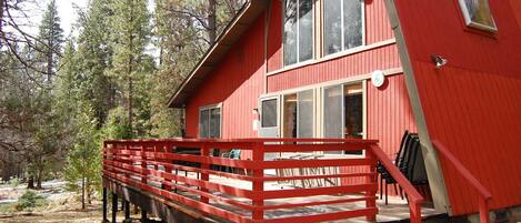 A red cabin with a wooden deck and a staircase leading to the entrance.