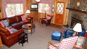 Ein gemütliches Blockhaus-Interieur mit einem braunen Ledersofa, einem blauen Sessel und einem Holztisch.