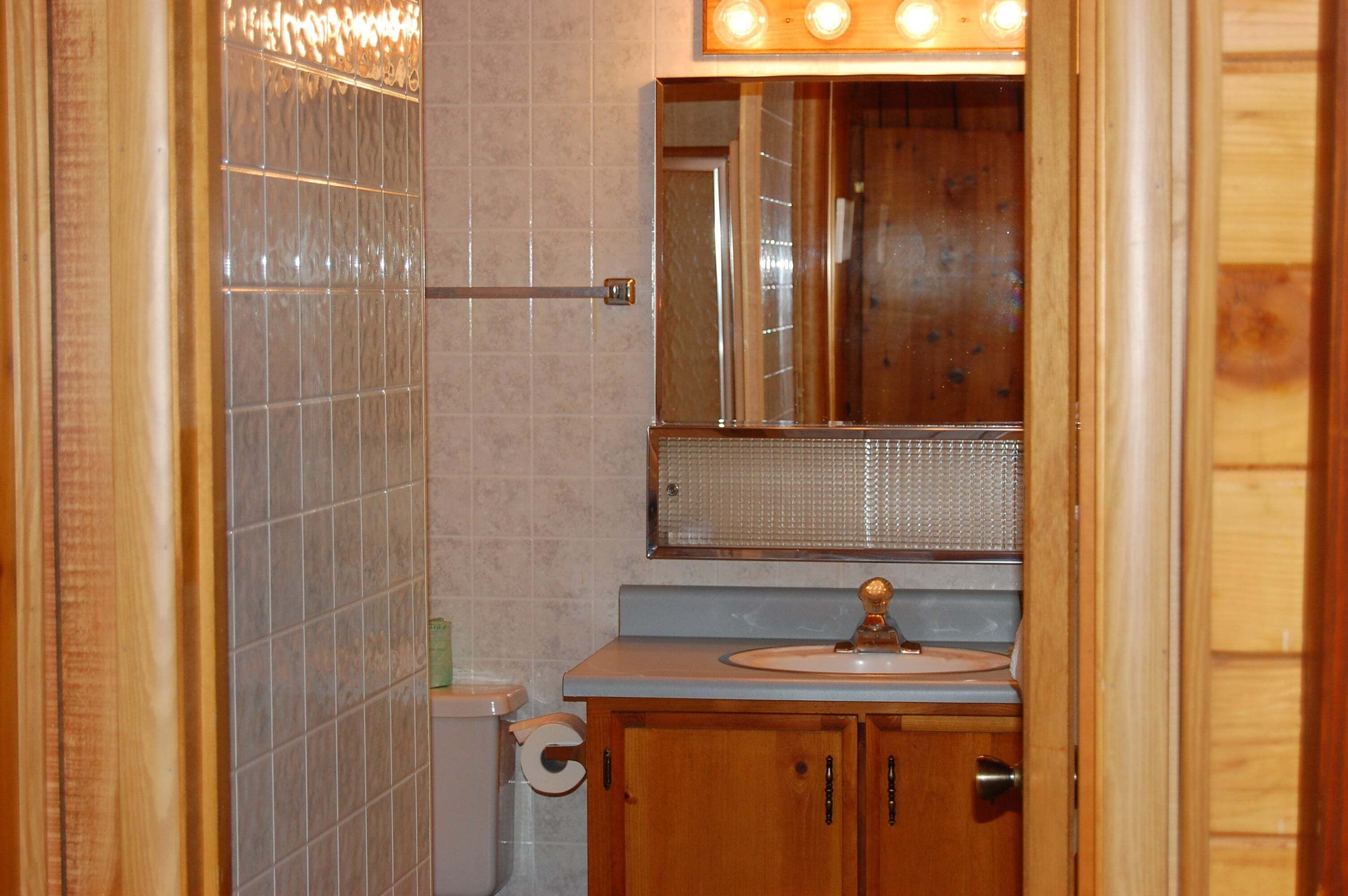 Une salle de bain avec un meuble-lavabo en bois, un miroir, un lavabo et un porte-serviettes.
