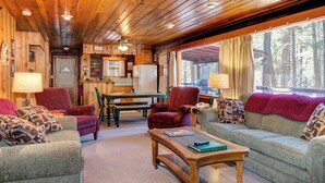 A cozy cabin interior with a wooden ceiling, a dining area, and a seating area with a sofa and armchairs. - Mia Mora (Yosemite National Park)