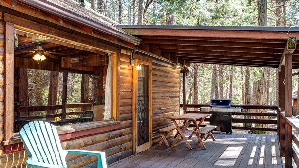 A wooden cabin with a covered porch, a grill, and a chair. - Mia Mora (Yosemite National Park)