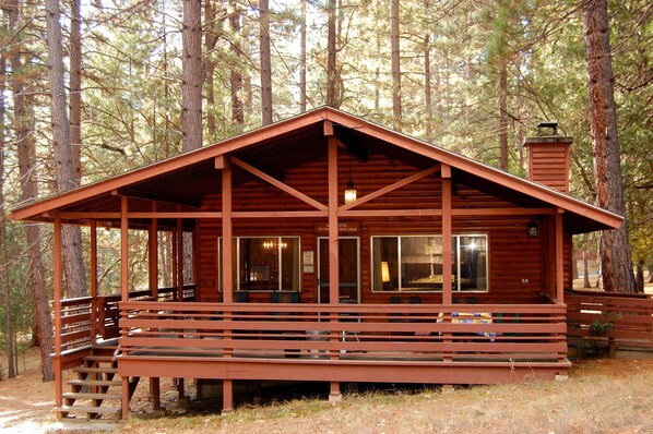 A wooden cabin with a porch, large windows, and a chimney. - Hasting's Hideaway (Yosemite National Park)