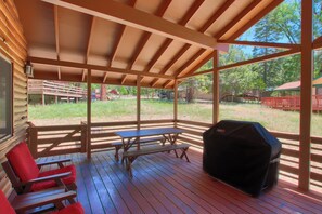 A covered outdoor area with a picnic table and chairs, a grill, and a view of the surrounding landscape. - Hasting's Hideaway (Yosemite National Park)