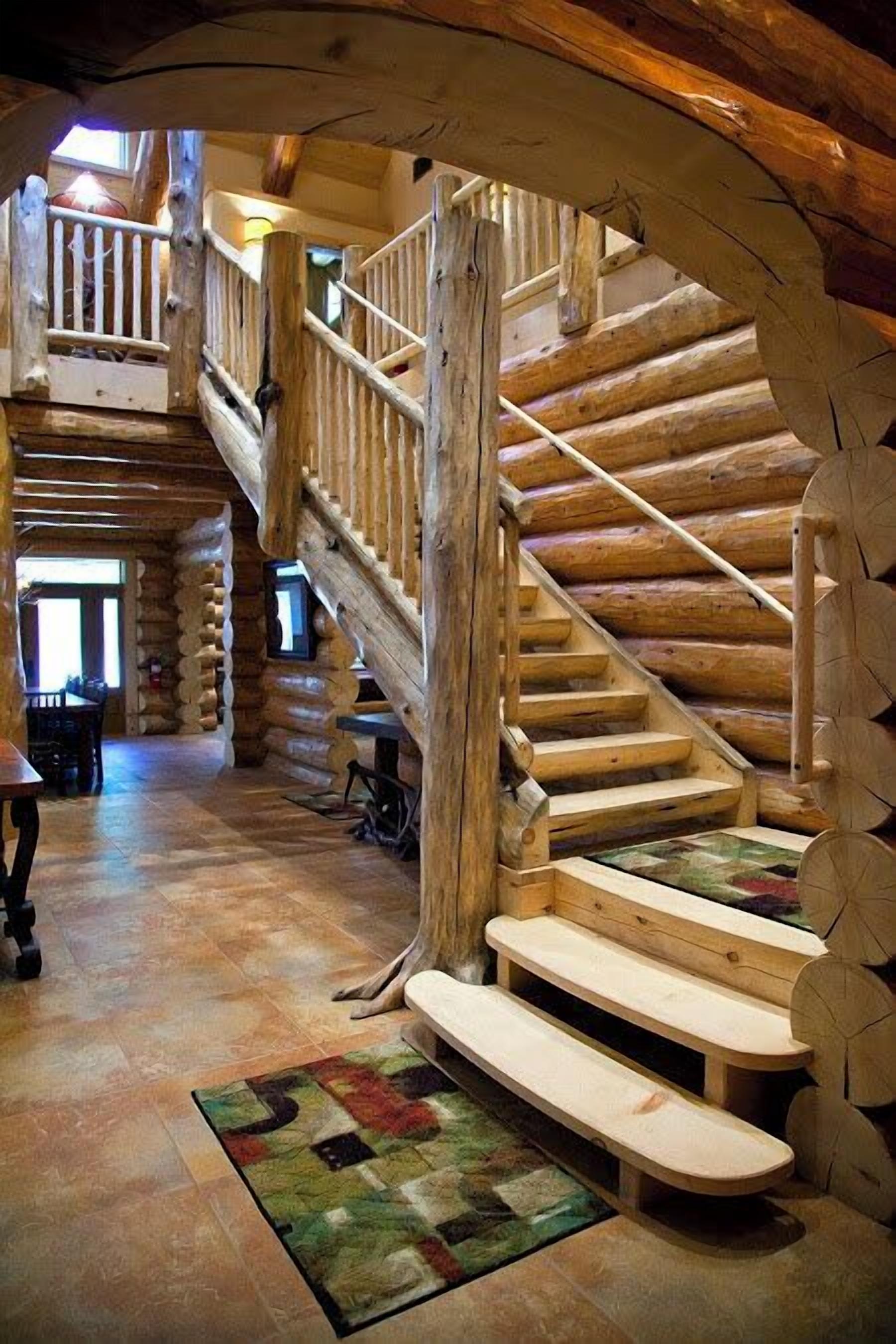 A log cabin interior with a wooden staircase leading to an upper level.