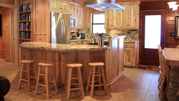 A wooden kitchen with a large island, bar stools, and a stainless steel refrigerator. - Grizzly Giant (Yosemite National Park)
