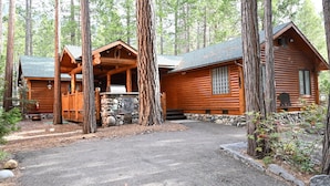 A log cabin with a porch and a stone foundation, surrounded by tall trees. - Grizzly Giant (Yosemite National Park)