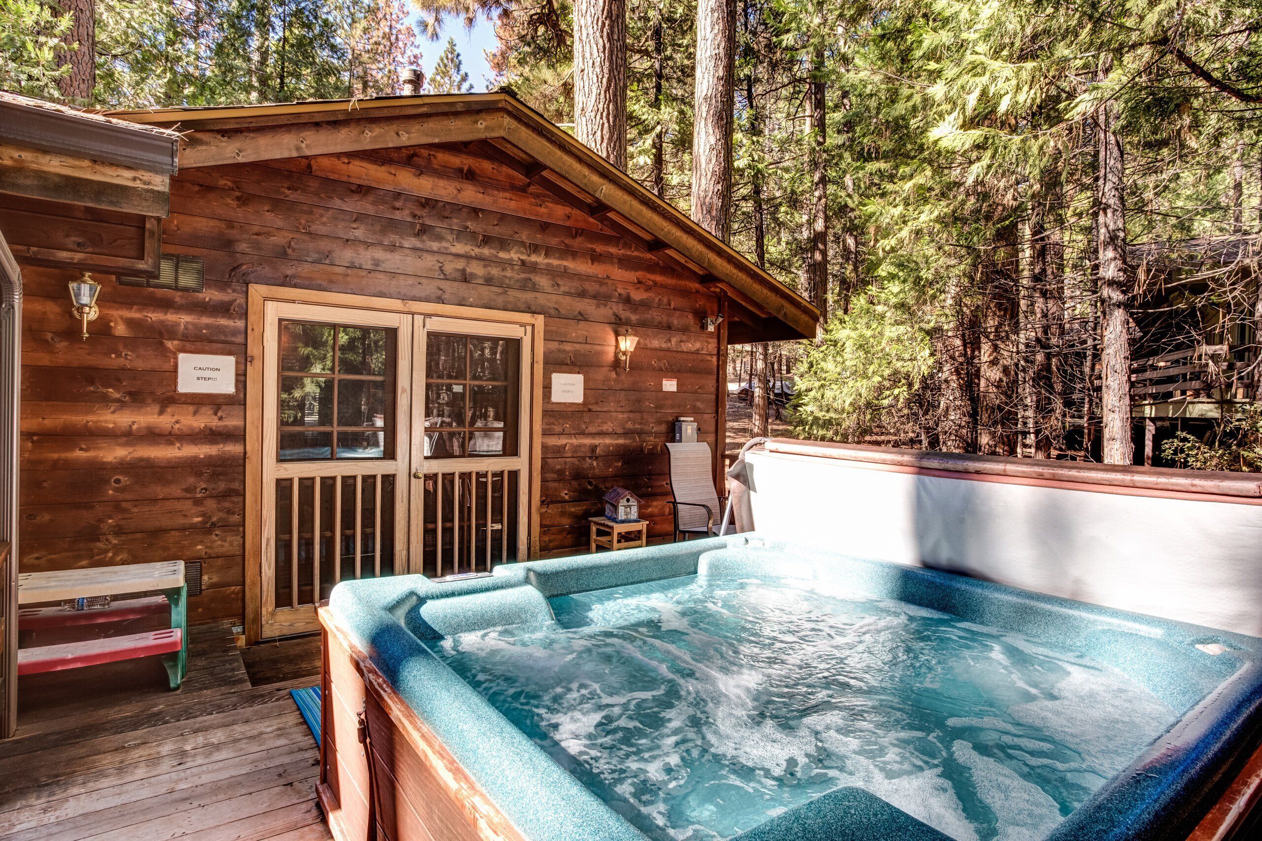 Una cabaña de madera con jacuzzi y terraza.