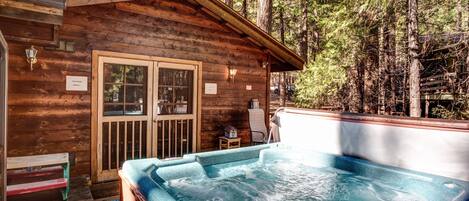 Una cabaña de madera con jacuzzi y terraza.