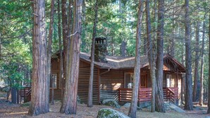 A rustic log cabin surrounded by tall trees. - Pine Creek Cabin (Yosemite National Park)