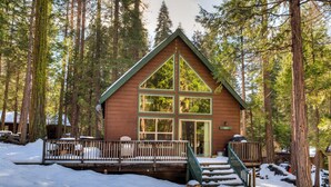 A cabin with a triangular roof, large windows, and a wooden deck. - Wawona Chalet (Yosemite National Park)