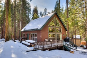 A cabin with a wooden exterior, large windows, a deck, and a snow-covered roof. - Wawona Chalet (Yosemite National Park)
