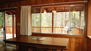 A wooden interior with a large window, a table, and a bench. - Harmony Villa (Yosemite National Park)
