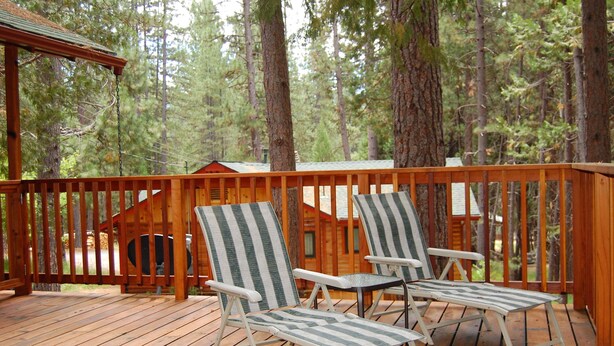 A wooden deck with two striped lounge chairs and a wooden cabin in the background. - Harmony Villa (Yosemite National Park)