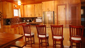 A wooden kitchen with a refrigerator, stove, and wooden chairs. - Harmony Villa (Yosemite National Park)