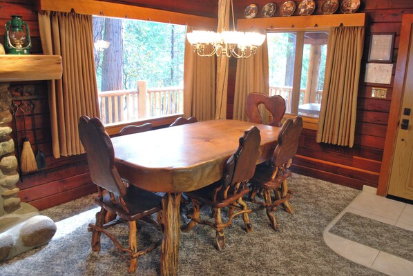 A wooden dining table with chairs, a chandelier, and curtains. - Half Dome (Yosemite National Park)