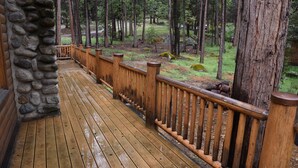 A wooden deck with a stone wall on one side, surrounded by a forested area. - Half Dome (Yosemite National Park)